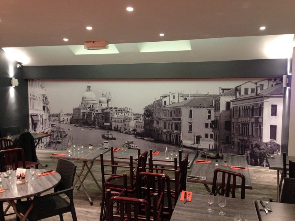 Photo d'un mur imprimé avec une vue d'Italie, dans une salle de restaurant inter-entreprise