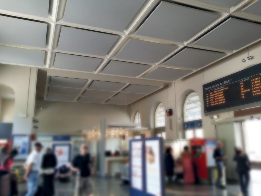 photo d'un hall de gare avec des cadres acoustiques coloris brun fixés au plafond