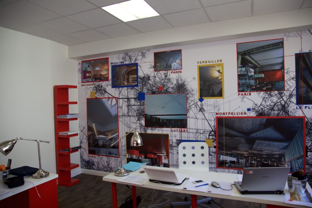 photo d'un mur imprimé dans un bureau avec un visuel cartographié des différentes réalisations de l'entreprise