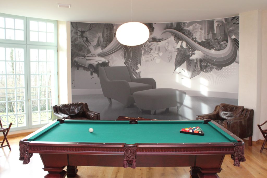 Photo d'une salle de détente avec un billard et un mur imprimé effet trompe l'oeil avec un fauteuil