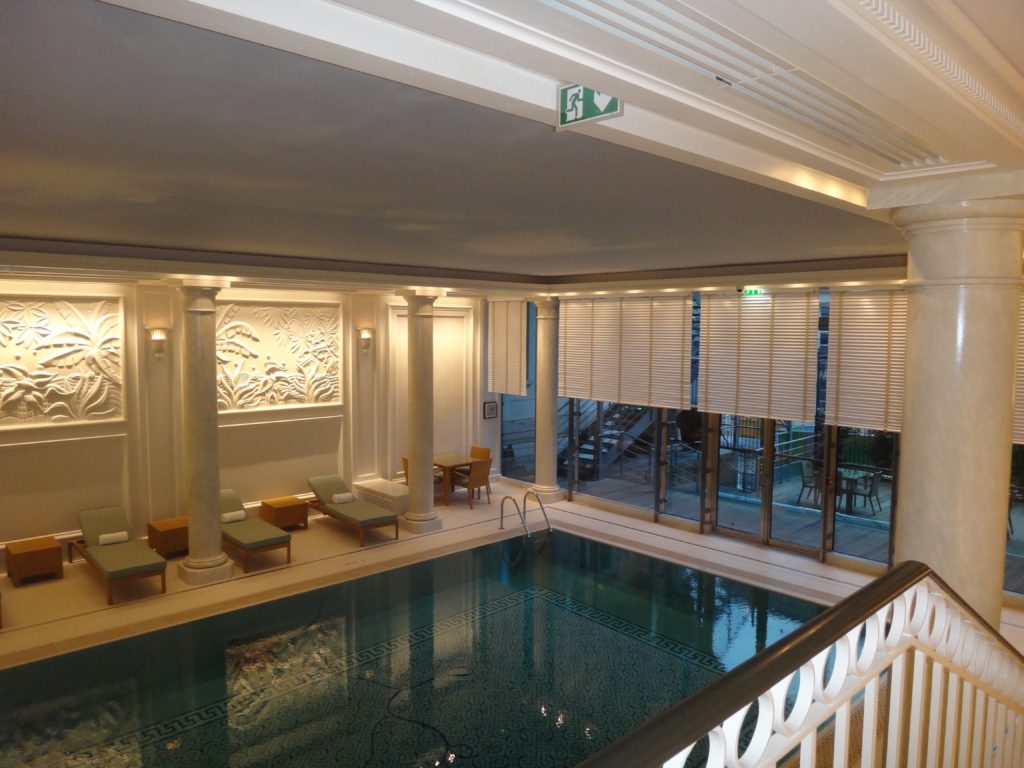 Photo d'un plafond imprimé acoustique avec un visuel de ciel nuageux au-dessus d'une piscine d'un hôtel