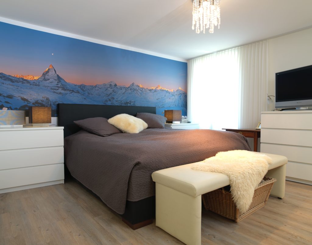 Photo d'une chambre à coucher avec un mur imprimé d'un visuel de montagne en tête de lit.