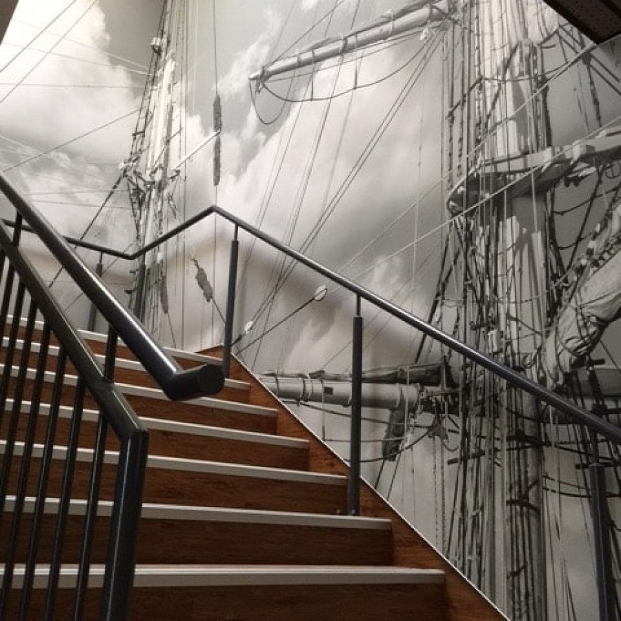 Photo d'un mur imprimé dans une montée d'escalier acec un visuel de mâts de bateau