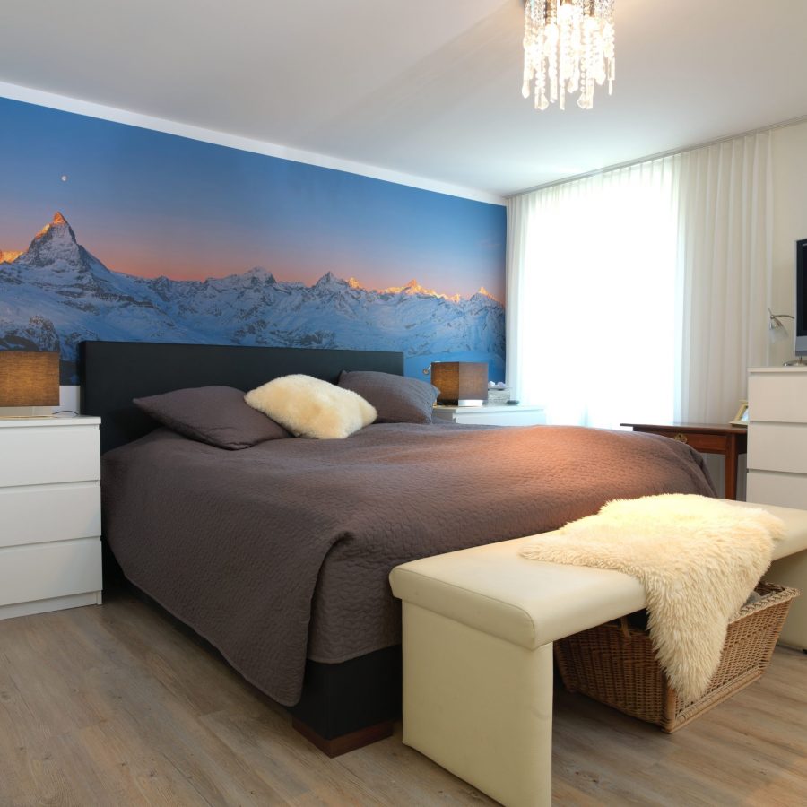 Photo d'une chambre à coucher avec un mur imprimé d'un visuel de montagne en tête de lit.